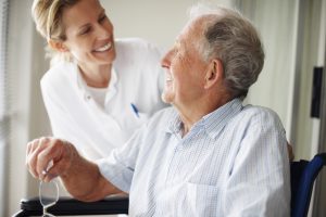 Happy retired man at the hospital speaking with a young nurse